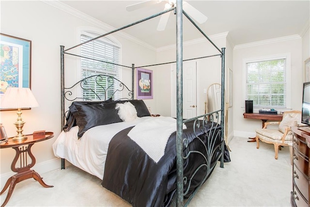 carpeted bedroom with crown molding, baseboards, and a ceiling fan