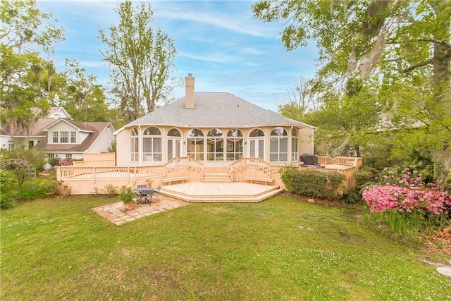back of house featuring a patio, a chimney, a deck, a lawn, and a sunroom