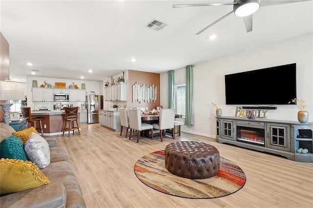 living room featuring recessed lighting, ceiling fan, visible vents, and light wood-style floors
