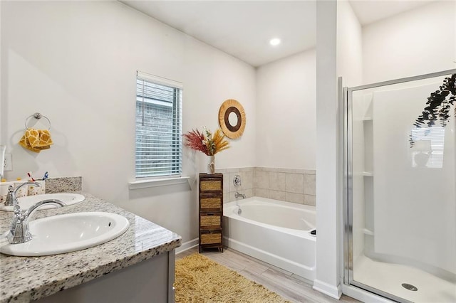 bathroom featuring a sink, a shower stall, a garden tub, and wood finished floors