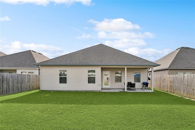 rear view of property with a lawn, a fenced backyard, a patio area, and roof with shingles