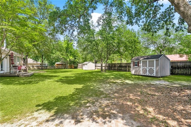 view of yard with a storage shed, an outbuilding, a fenced backyard, and a wooden deck