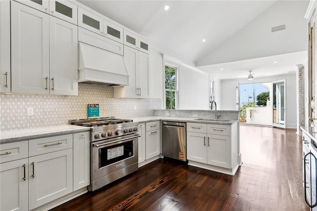 5700 Annunciation St, New Orleans, LA 70115 - kitchen with appliances with stainless steel finishes, a sink, a peninsula, dark wood-type flooring, and custom exhaust hood