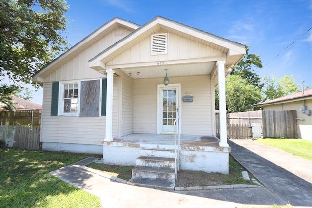 bungalow with covered porch, fence, board and batten siding, and concrete driveway