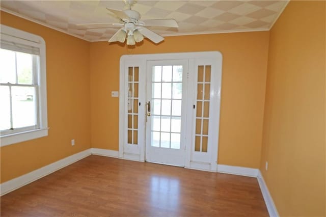 doorway with plenty of natural light, baseboards, crown molding, and wood finished floors