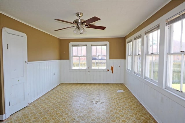 spare room featuring crown molding, ceiling fan, and wainscoting