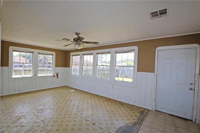 empty room with a ceiling fan, wainscoting, and visible vents