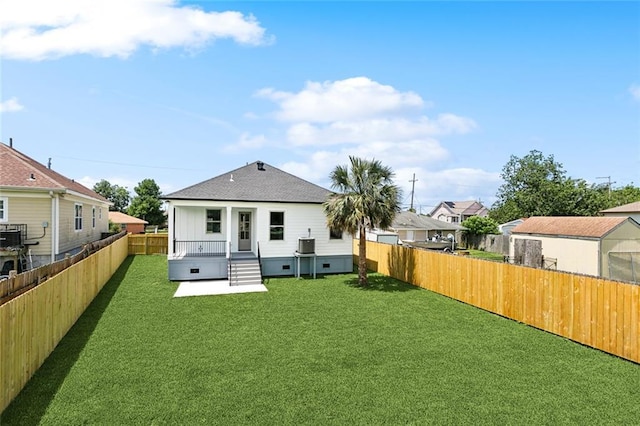rear view of property featuring a lawn, a fenced backyard, a residential view, and a shingled roof
