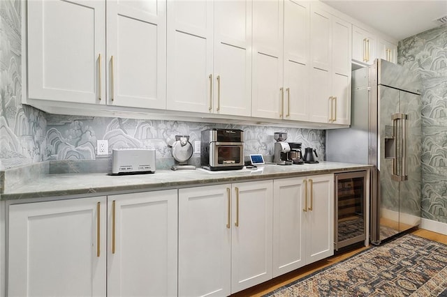 bar featuring high end fridge, wine cooler, wood finished floors, and tasteful backsplash