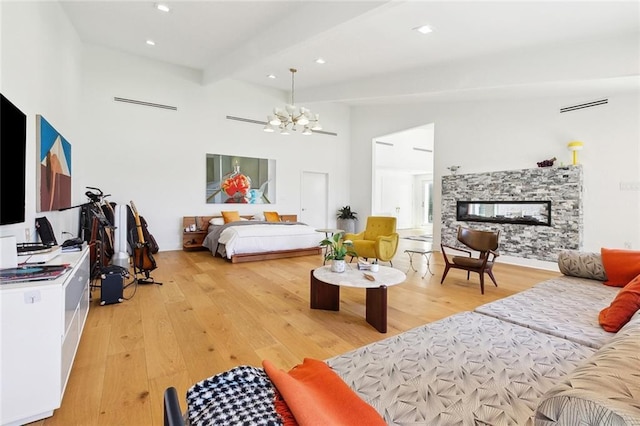 bedroom featuring an inviting chandelier, light wood-style floors, recessed lighting, and a stone fireplace