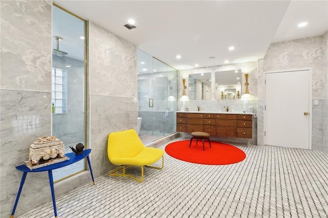full bath with double vanity, tile walls, recessed lighting, and a stall shower