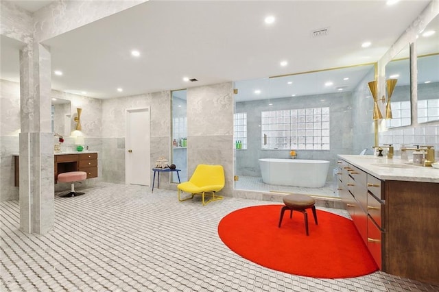 full bathroom featuring a healthy amount of sunlight, tile walls, a soaking tub, and vanity
