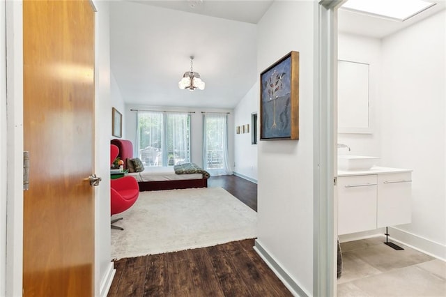bedroom featuring baseboards, a chandelier, a sink, and wood finished floors