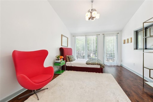 bedroom with baseboards, lofted ceiling, wood finished floors, and a chandelier