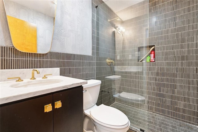 full bathroom with toilet, tile walls, tiled shower, and vanity