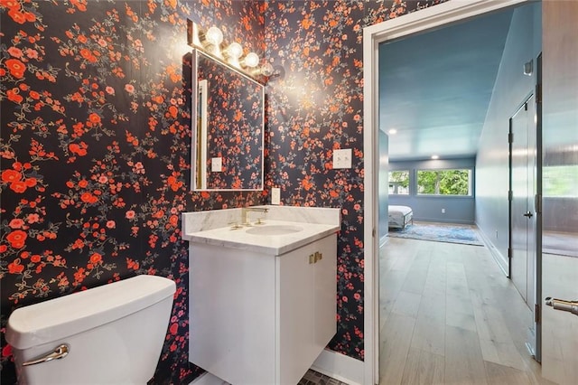 5640 Bancroft Dr, New Orleans, LA 70122 - ensuite bathroom featuring baseboards, wood finished floors, wallpapered walls, toilet, and vanity