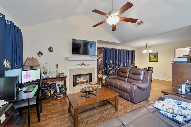 living room featuring visible vents, wood finished floors, lofted ceiling, a tile fireplace, and ceiling fan with notable chandelier