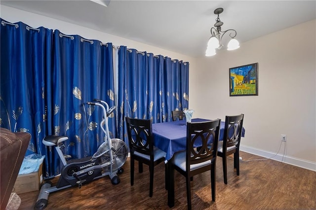 dining area featuring baseboards, wood finished floors, and a chandelier