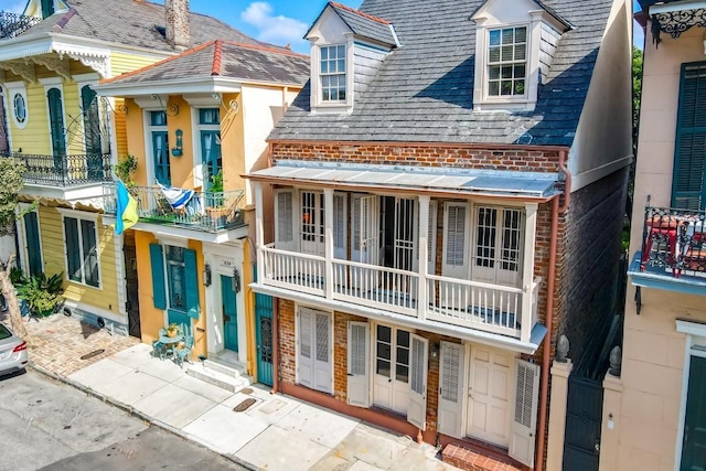 825 Barracks St, New Orleans, LA 70116 - view of front of house with a high end roof, a balcony, and brick siding