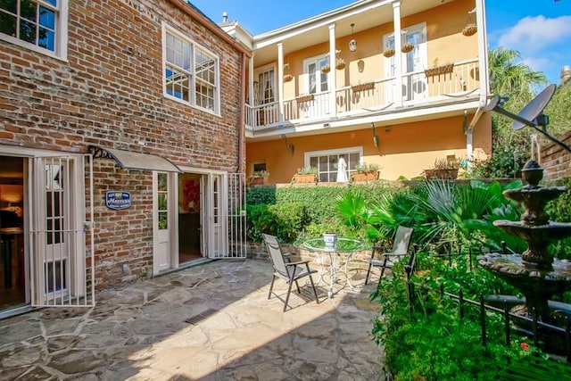 825 Barracks St, New Orleans, LA 70116 - back of property with stucco siding, a patio area, a balcony, and brick siding