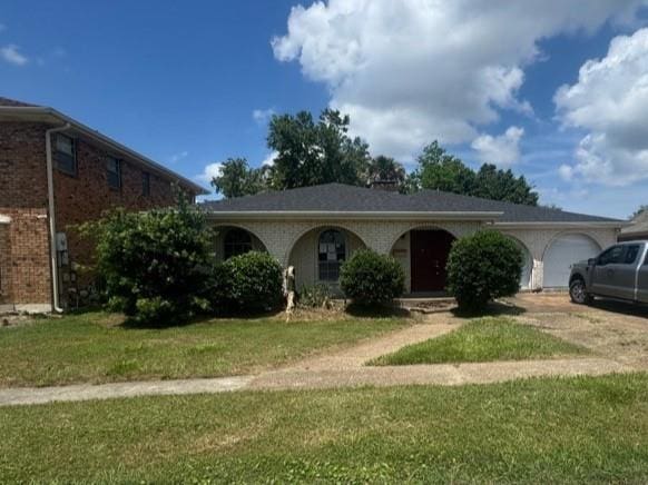 ranch-style house featuring concrete driveway, an attached garage, and a front lawn