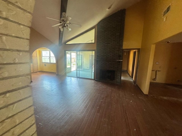 unfurnished living room featuring ceiling fan, arched walkways, a brick fireplace, high vaulted ceiling, and hardwood / wood-style floors