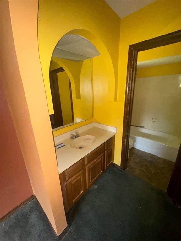 bathroom featuring vanity, toilet, and a washtub