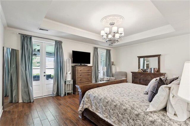 bedroom featuring multiple windows, ornamental molding, a tray ceiling, and a chandelier