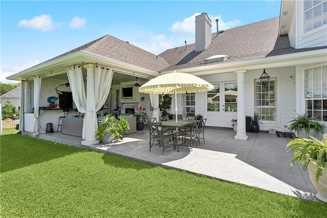 back of property with a shingled roof, a fireplace, a chimney, a patio, and a yard