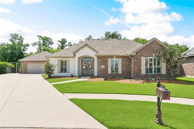 single story home featuring french doors, driveway, a front lawn, and brick siding