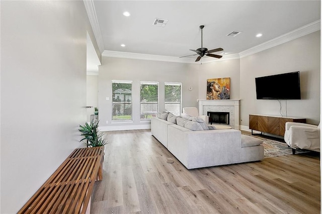 living room featuring crown molding, a ceiling fan, and light wood-style flooring