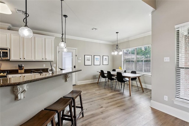 kitchen featuring visible vents, baseboards, stainless steel microwave, and a kitchen breakfast bar
