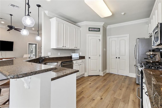 kitchen with visible vents, a sink, ornamental molding, stainless steel appliances, and white cabinetry