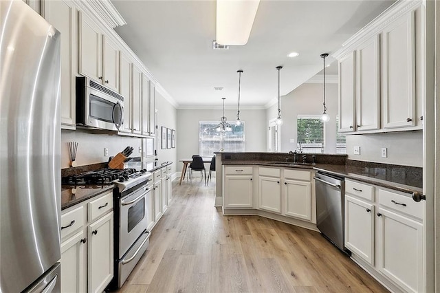 kitchen with crown molding, light wood-type flooring, a sink, a peninsula, and stainless steel appliances