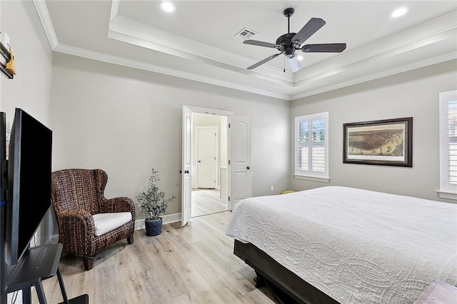 bedroom featuring visible vents, ornamental molding, baseboards, a raised ceiling, and light wood-style flooring