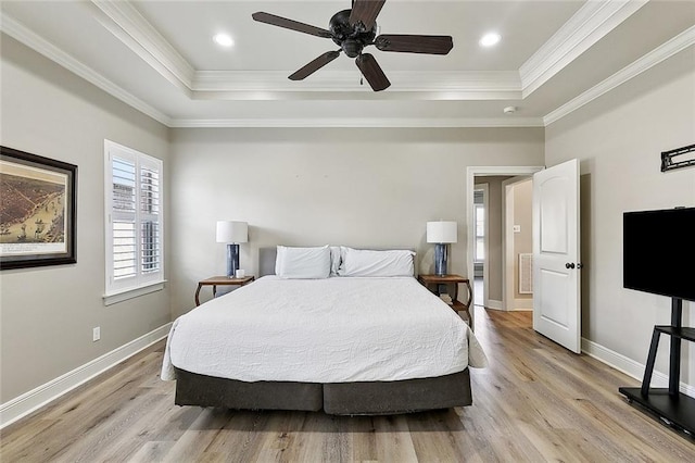bedroom featuring a tray ceiling, baseboards, and light wood finished floors