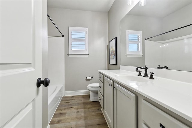 full bath with vanity, toilet, baseboards, shower / washtub combination, and wood finished floors