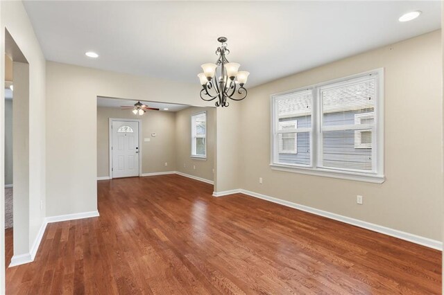 empty room featuring baseboards, recessed lighting, ceiling fan with notable chandelier, and wood finished floors