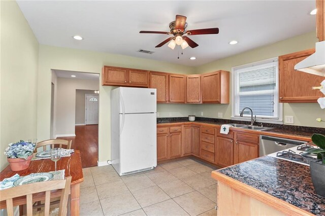 kitchen with a sink, dark countertops, freestanding refrigerator, and a ceiling fan