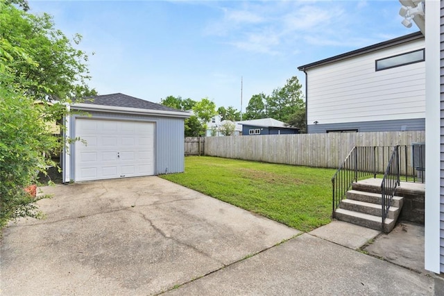 view of yard with fence, driveway, an outdoor structure, and a garage