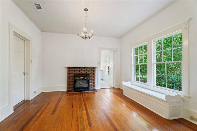 328 E St, Mandeville, LA 70448 - unfurnished living room with visible vents, a fireplace, baseboards, wood-type flooring, and a notable chandelier