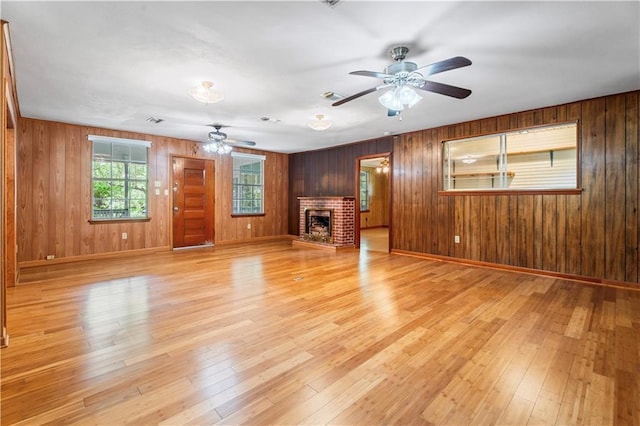 328 E St, Mandeville, LA 70448 - unfurnished living room featuring wooden walls, a ceiling fan, light wood finished floors, and a brick fireplace