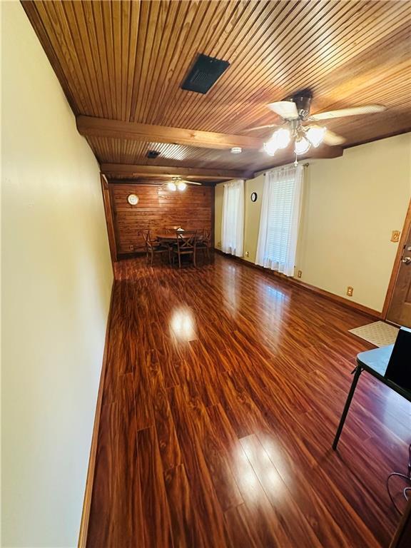 unfurnished living room with ceiling fan, wood finished floors, and wooden ceiling