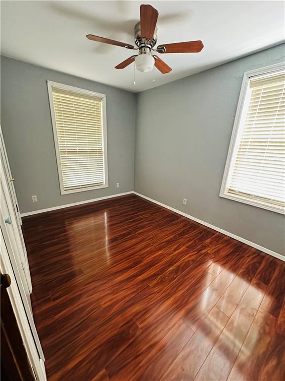 spare room featuring baseboards, ceiling fan, and wood finished floors