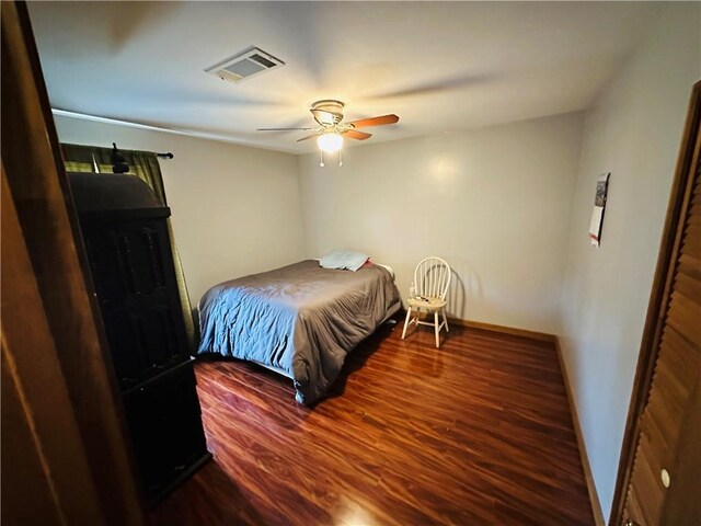 bedroom with baseboards, a ceiling fan, wood finished floors, and visible vents