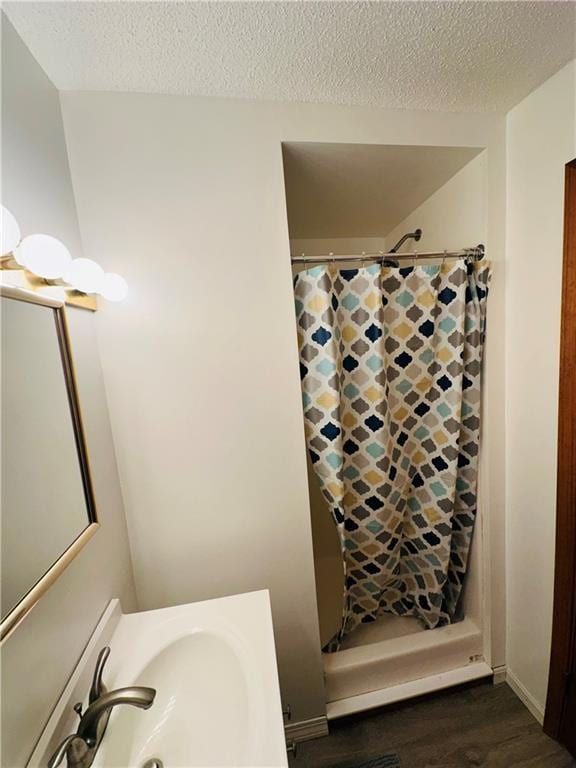 bathroom with a sink, a textured ceiling, curtained shower, and wood finished floors