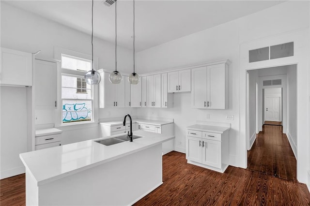 180002 Franklin Ave, New Orleans, LA 70117 - kitchen featuring white cabinets, dark wood-style floors, a kitchen island with sink, pendant lighting, and light countertops