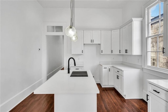 180002 Franklin Ave, New Orleans, LA 70117 - kitchen with a center island with sink, white cabinetry, dark wood-style flooring, decorative light fixtures, and healthy amount of natural light