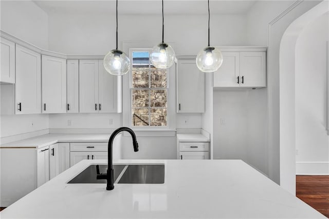 180002 Franklin Ave, New Orleans, LA 70117 - kitchen featuring white cabinets, pendant lighting, arched walkways, and wood finished floors