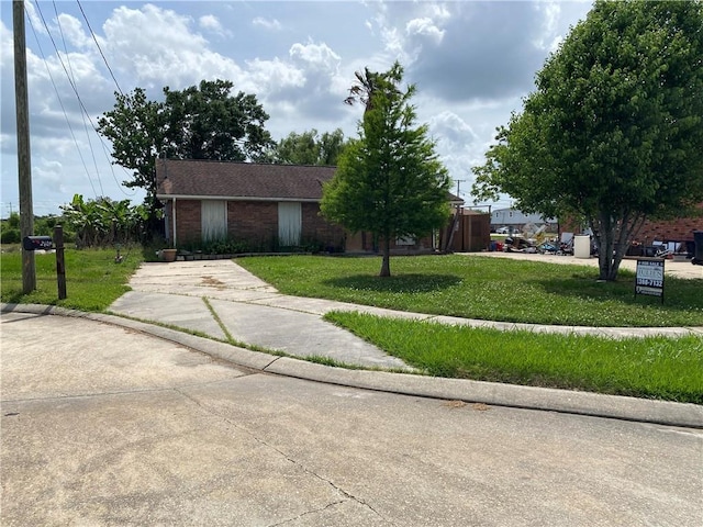 ranch-style home featuring brick siding, a front lawn, and concrete driveway